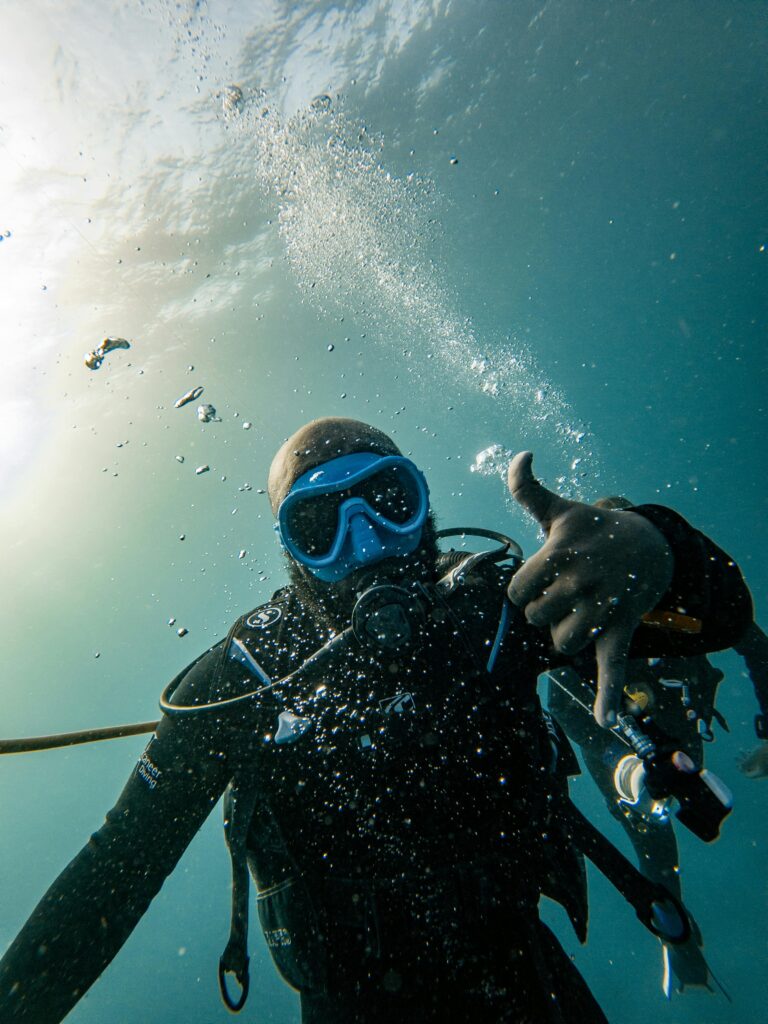 Scuba diver in Zanzibar's clear waters gives OK signal, surrounded by bubbles underwater.